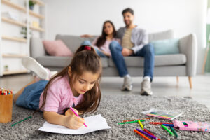 The Carpet Cleaners - Family happiness. Cute girl drawing with colorful pencils, lying on floor carpet while parents relaxing on sofa