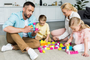 The Carpet Cleaners - family with two little children sitting on carpet and playing with colorful blocks
