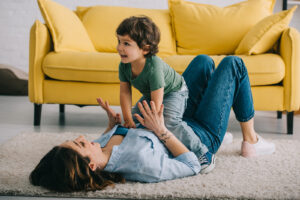 The Carpet Cleaners - Happy mother and son playing on carpet in living room